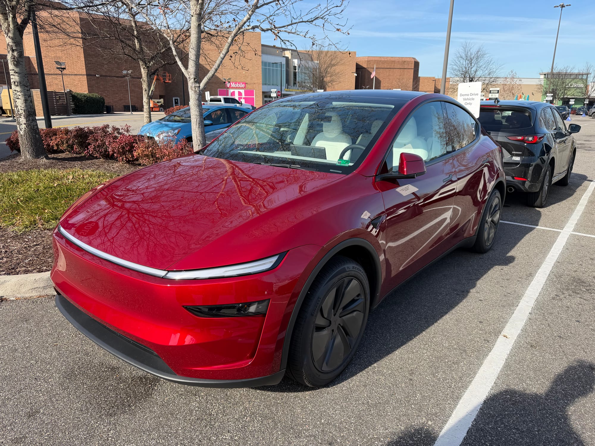 A red Tesla Model Y sitting in a parking lot.