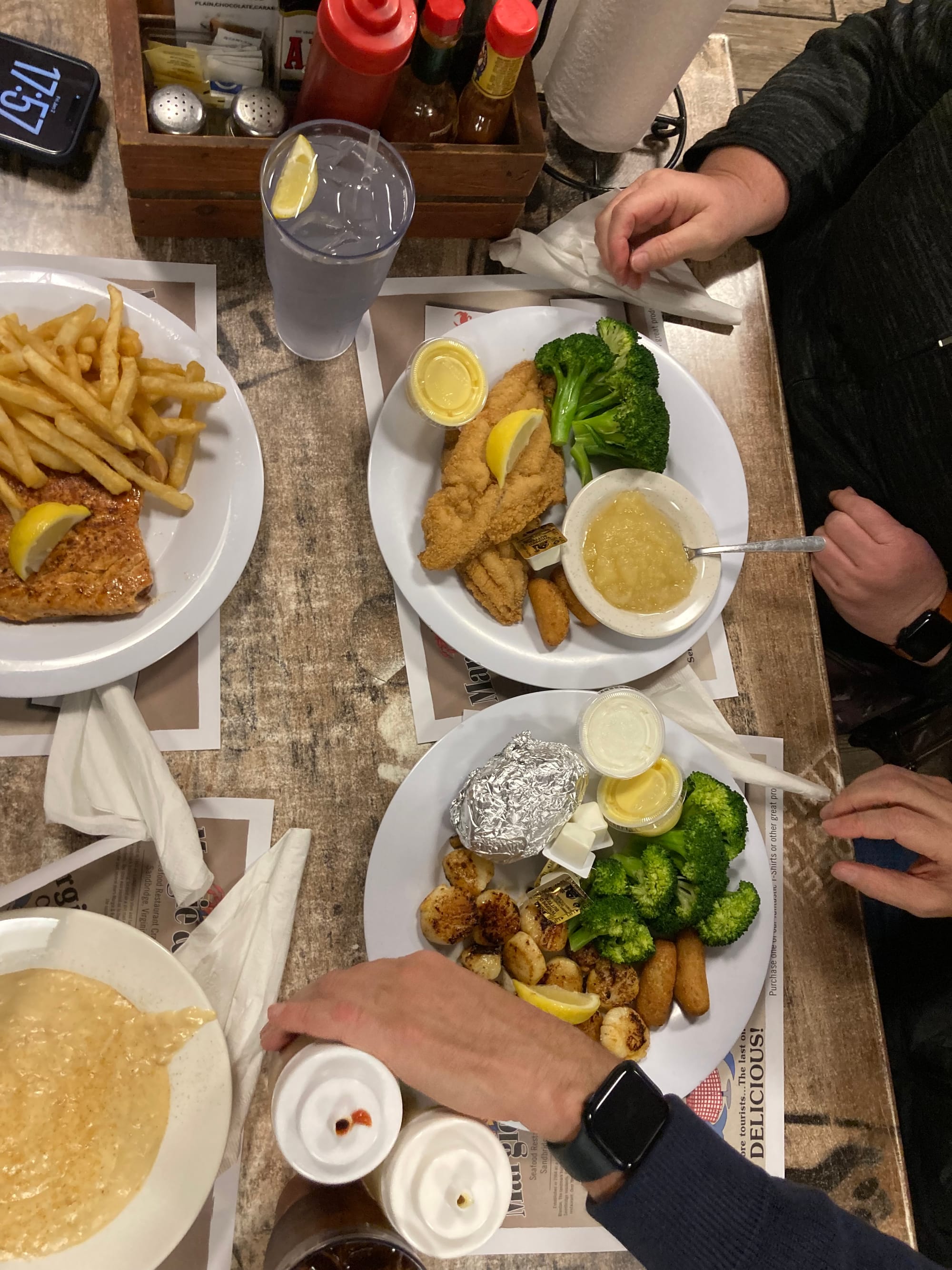 A plate of salmon and fries in the top left, catfish in the top right, she crab soup on the bottom left, and scallops on the bottom right.