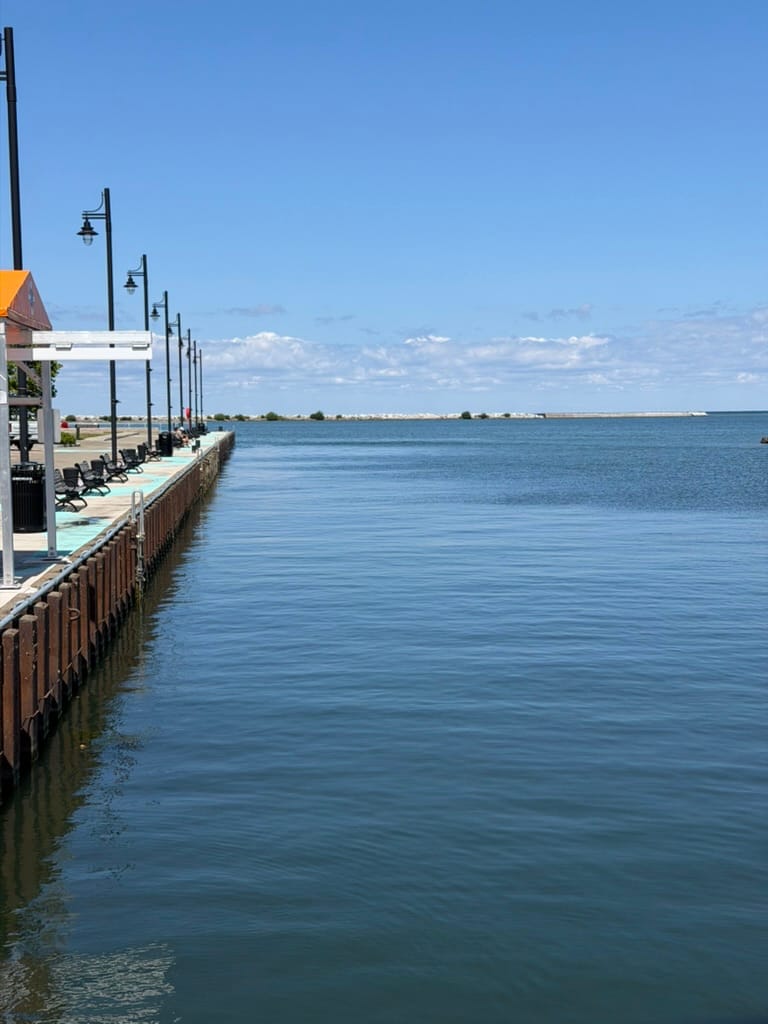 A view off the beginning of the pier. The pier is on the left with light poles regularly spaced and the lake on the right.