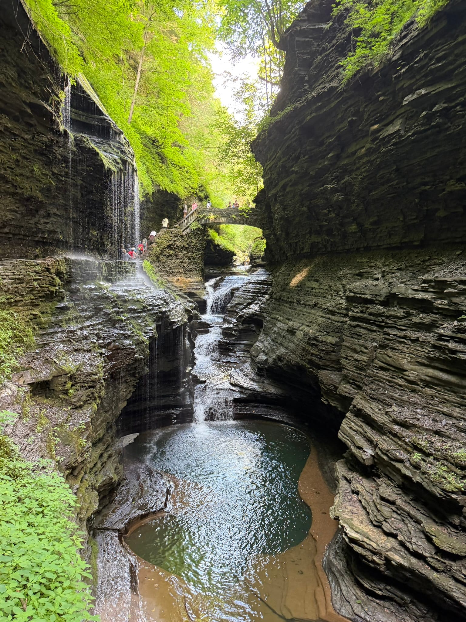 A shot straight down the Glen with a pool of water in the foreground with waterfalls flowing in from the back and left.