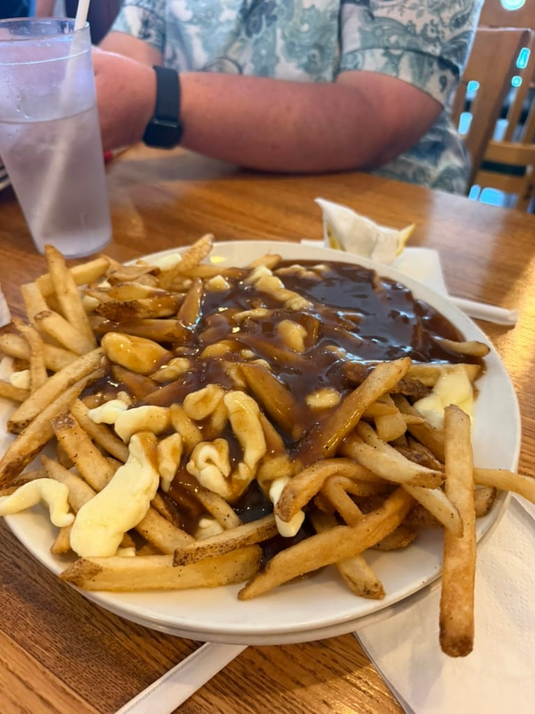 A big plate of poutine; fries topped with gravy and cheese curds.