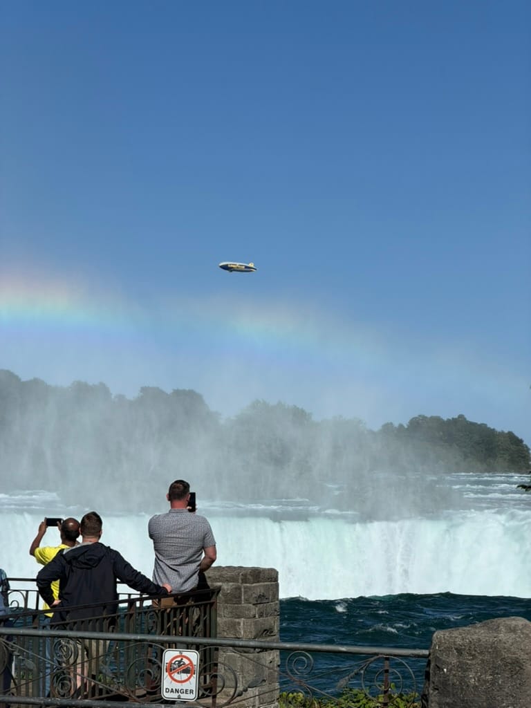 A zoomed in picture of the falls with the Goodyear blimp in the background.