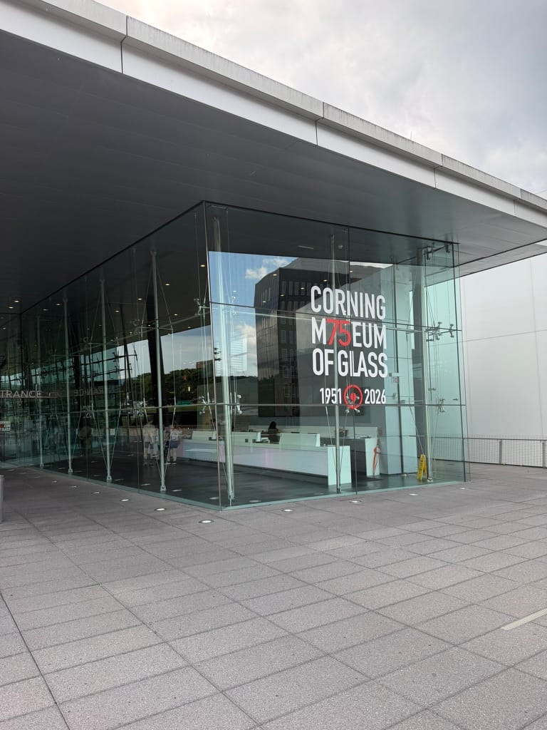 The glass sided entrance to the museum with the text "Corning Museum of Glass" printed on it.