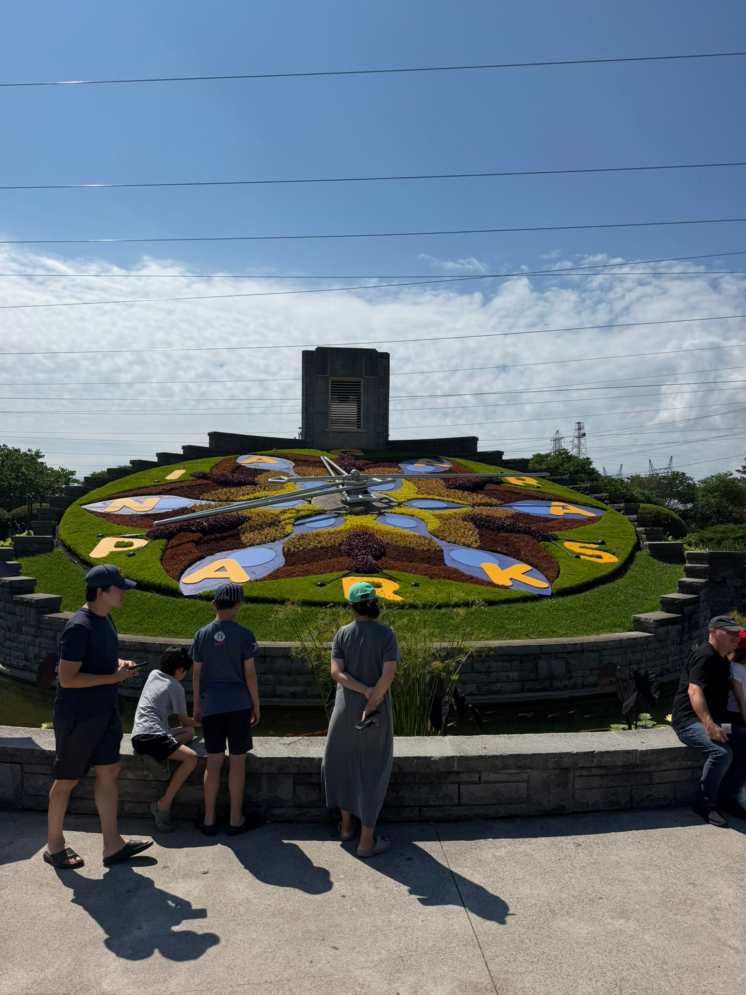 A huge clock on a slant with flowers around it and "Niagara Parks" written around it instead of numbers.