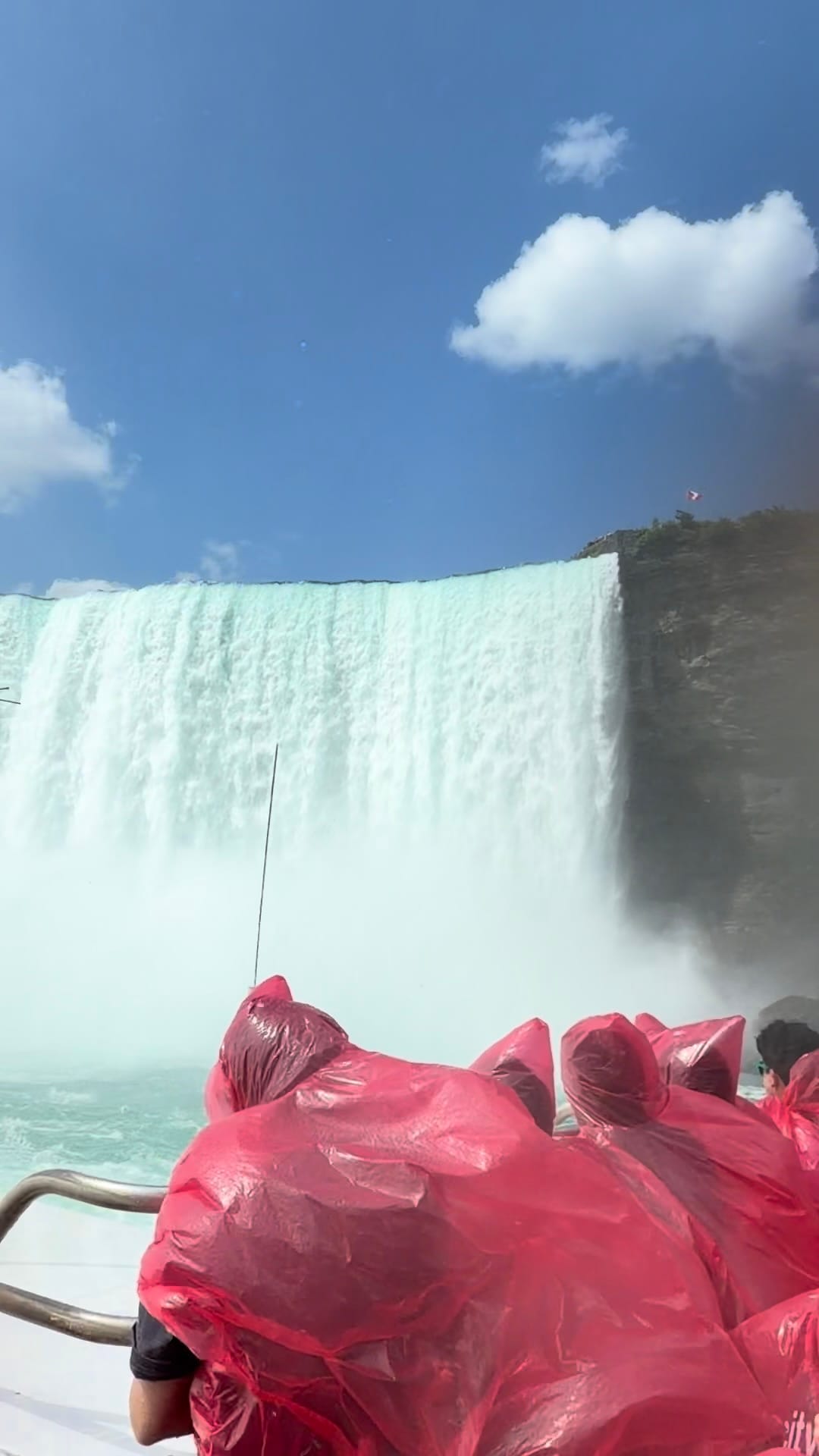 Horseshoe Falls from the boat in the river looking up toward the top. People in red ponchos are trying to not get wet.